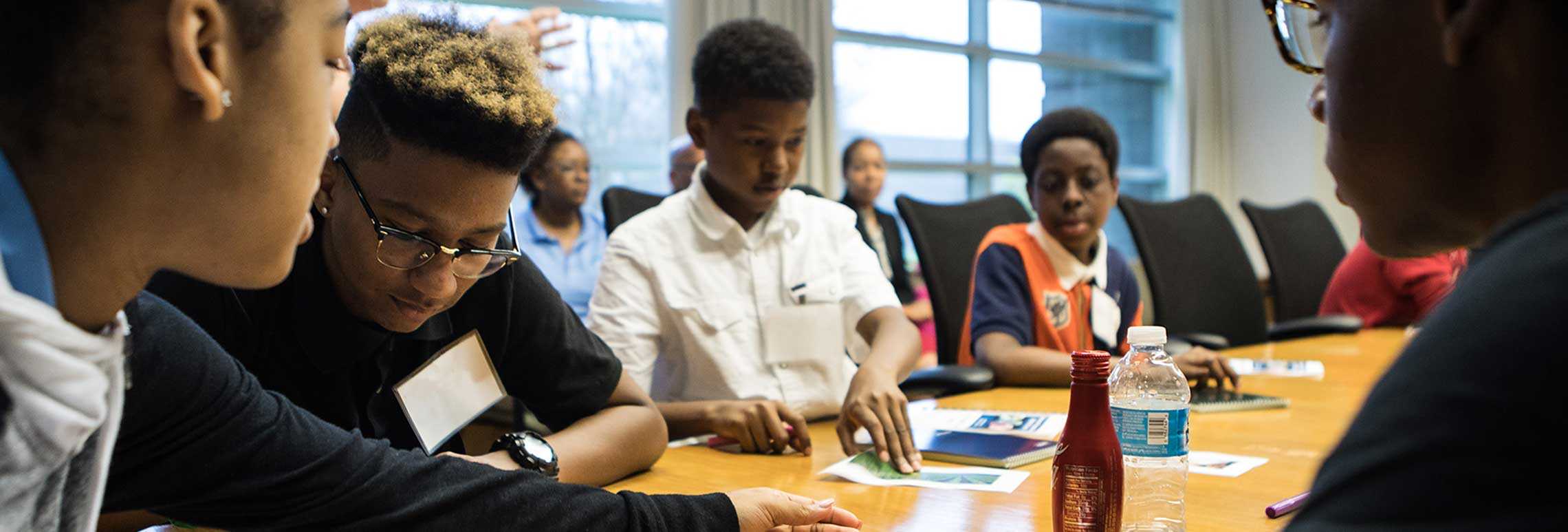 Services banner with a group of children sitting around a table, engaged in a meeting